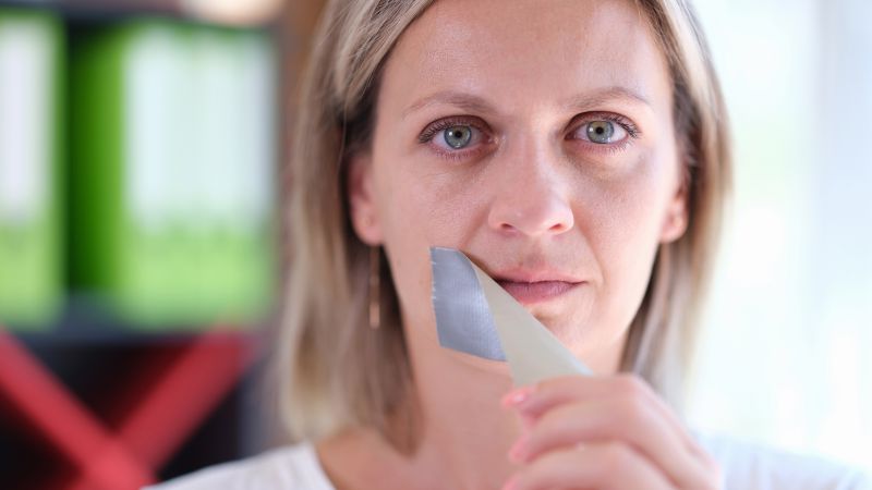 Woman removing tape from her mouth