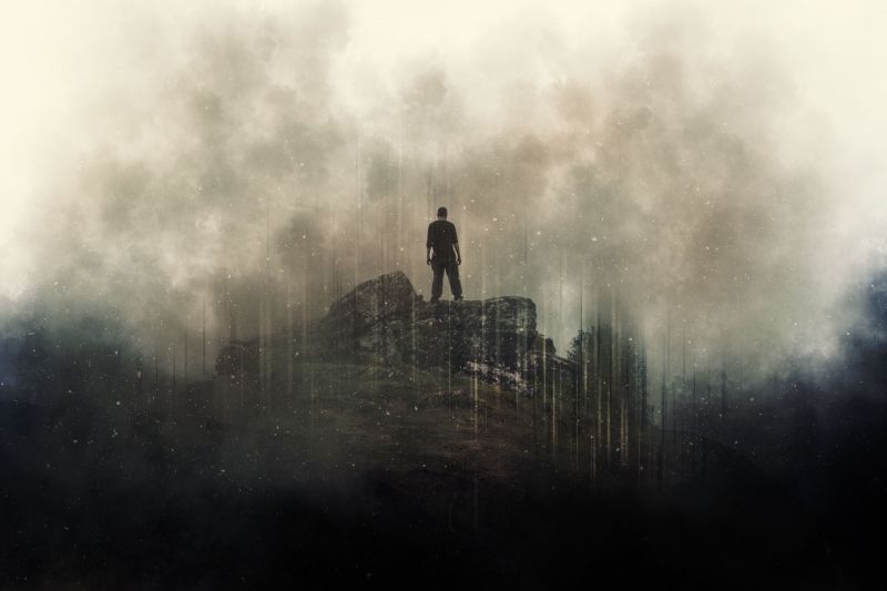 Depicting man making stand on top of dark mountain