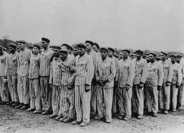 Shutterstock Image:  “Roll call at Buchenwald concentration camp, ca.1938-1941. Two prisoners in the foreground are supporting a comrade, as fainting was frequently an excuse for the guards to ‘liquidate’ useless inmates.”