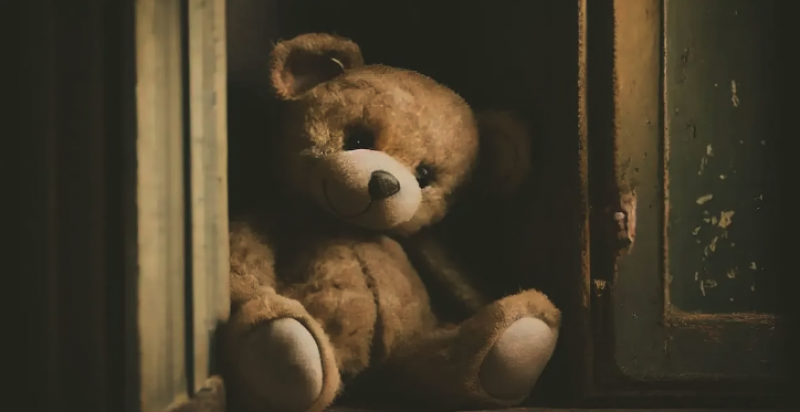 Image of Stuffed teddy bear in a dark corner